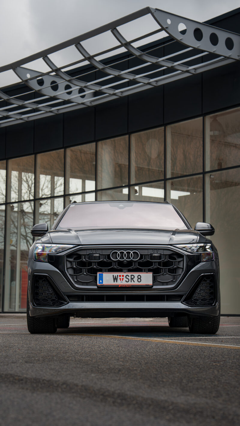 Audi Q8 front view photographed in front of modern glass architecture